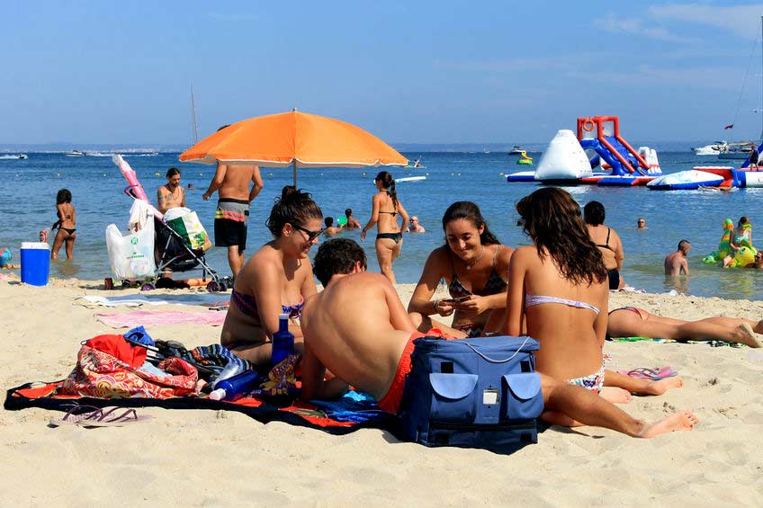 En flok unge mennesker slapper af og hygger sig på stranden i Palma Nova